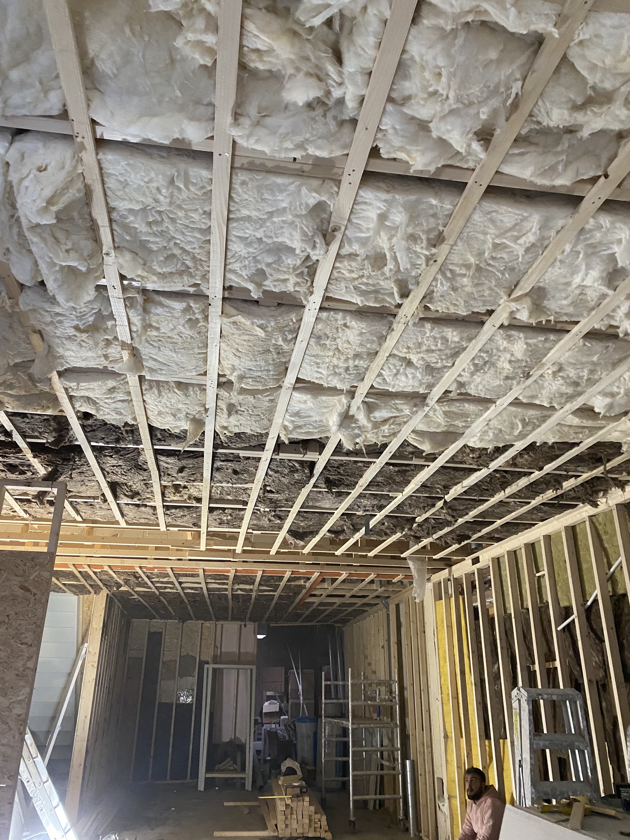 Opengewerkt plafond met houten regelwerk en isolatie, stijlwerk langs de wand