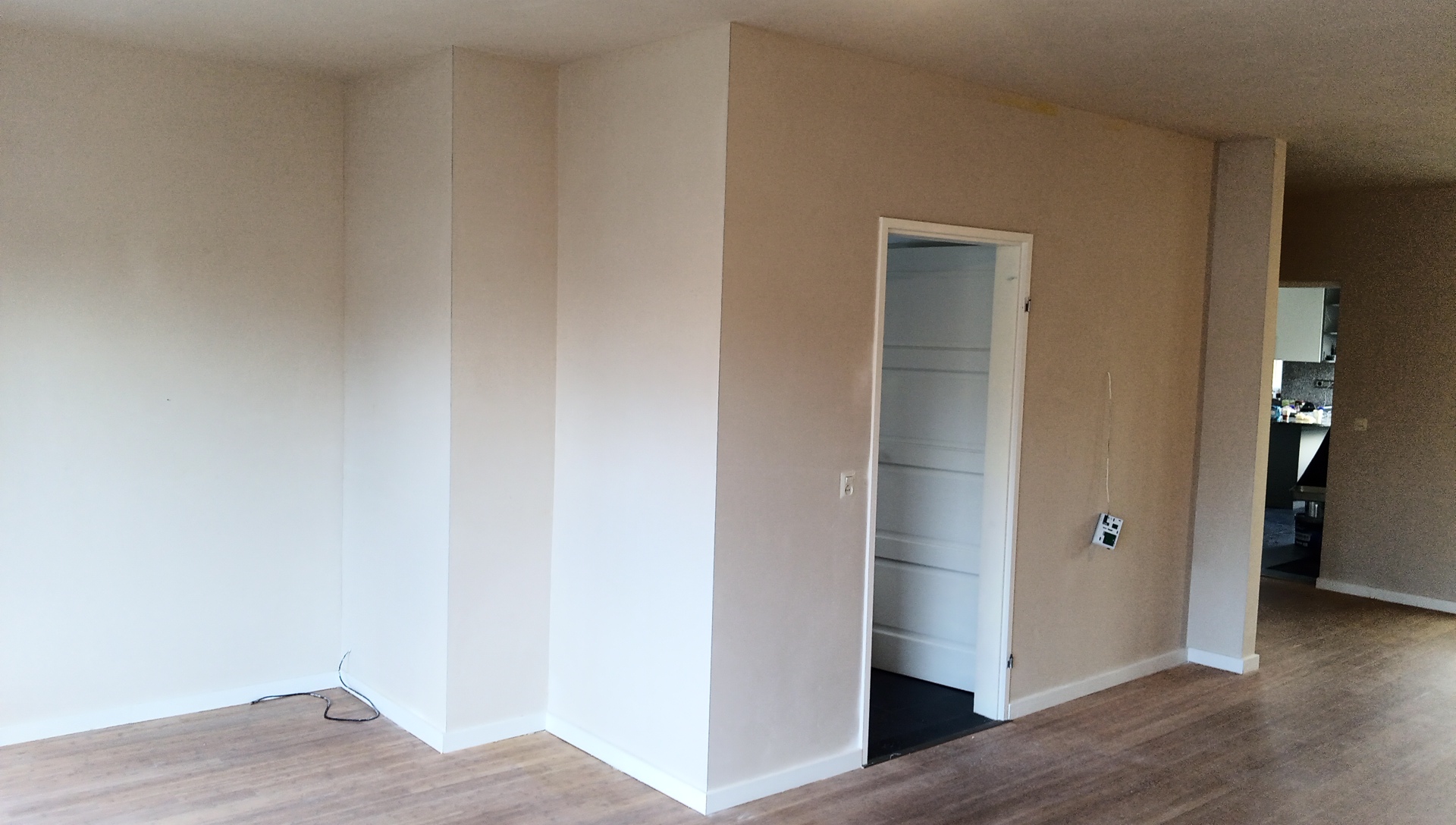Afgewerkte kamer met strakke lichte wanden en een houten vloer