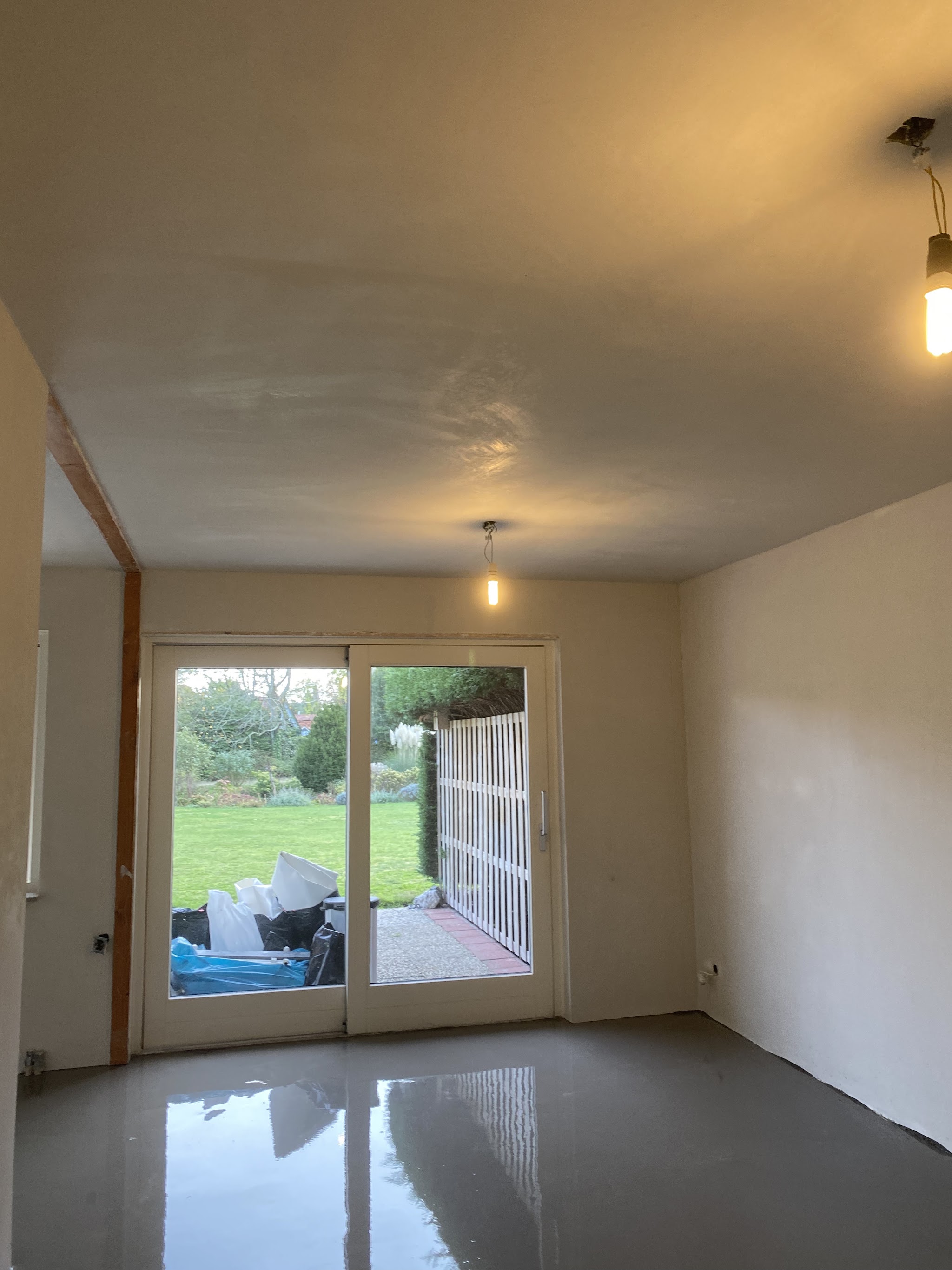 Opgeleverde woonkamer met strak gestucte witte wanden en plafond