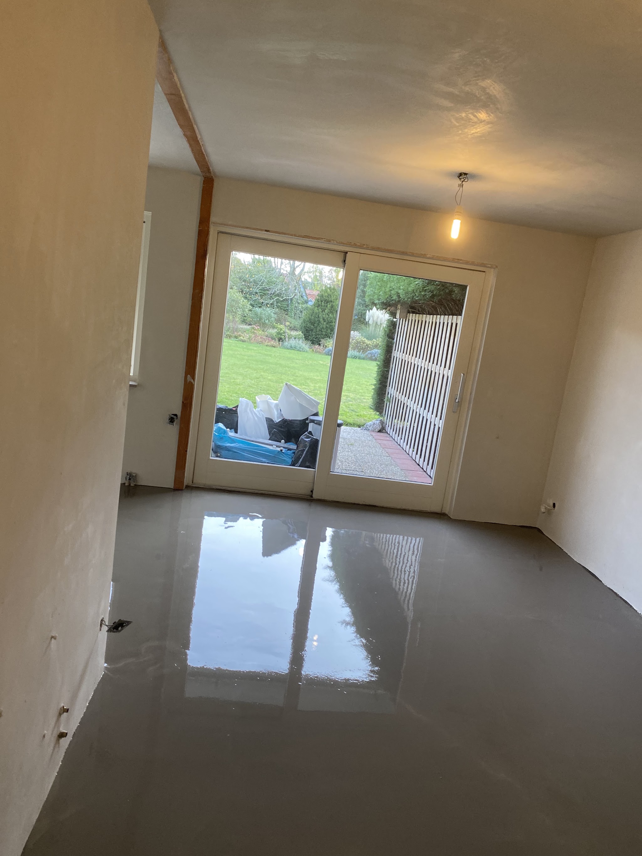 Opgeleverde woonkamer met strakke witte wanden en tuindeuren